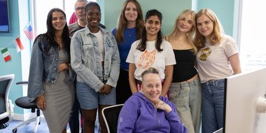 Ops team huddle by laptop looking at the camera smiling