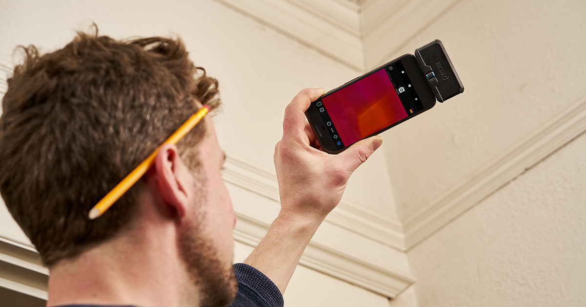 Person using thermal camera on their smartphone facing towards wall