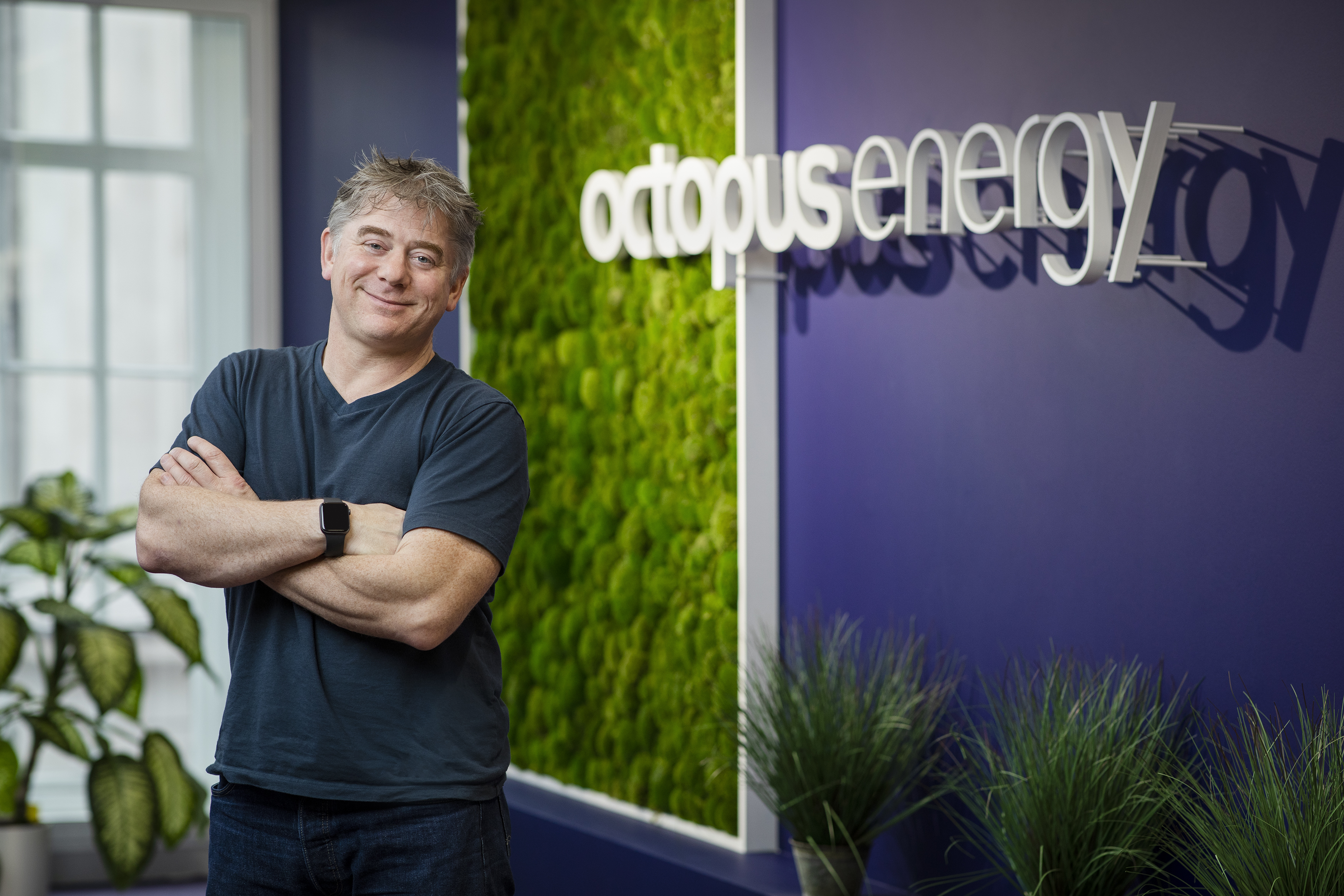 An image of Greg, smiling with his arms folded