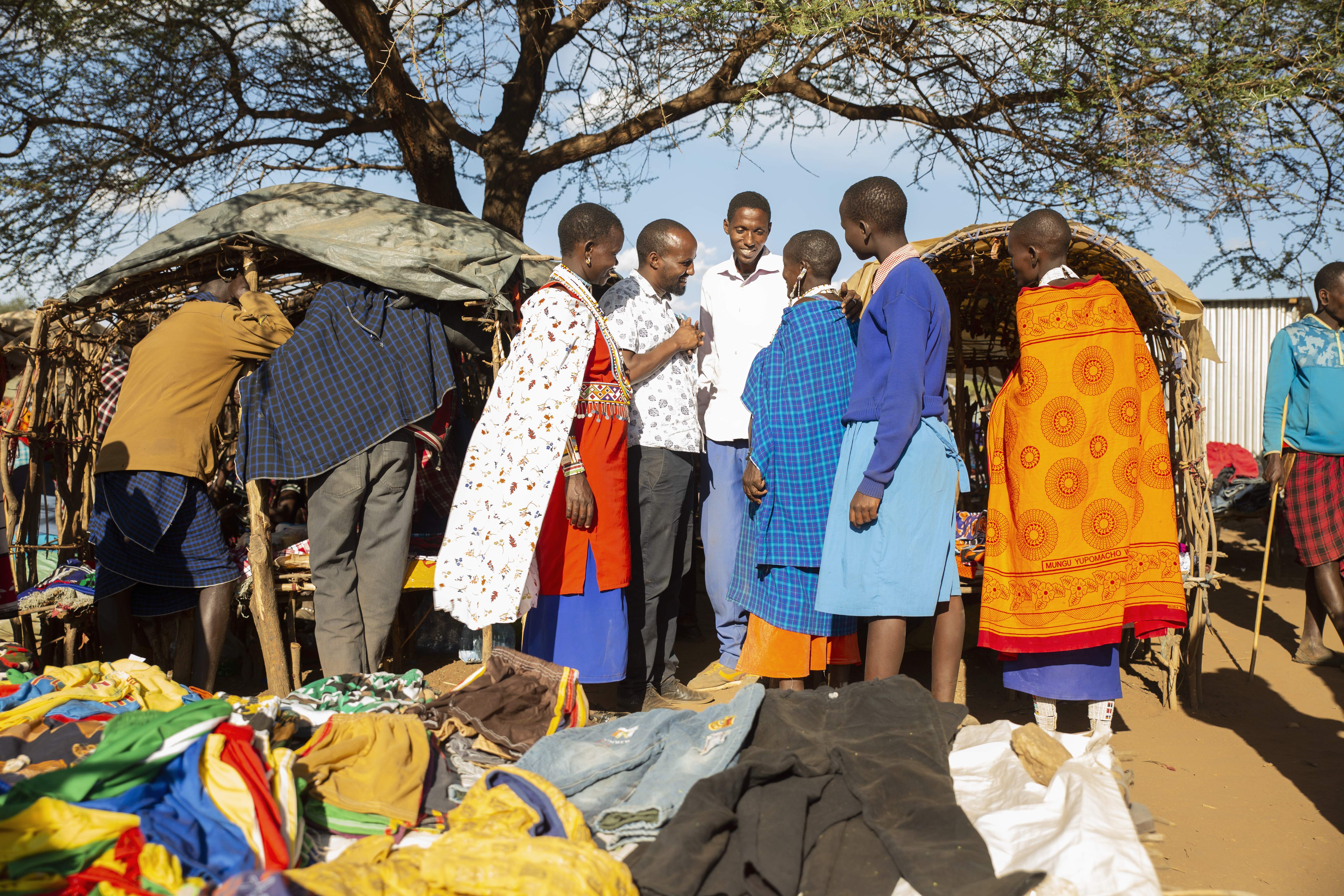 a group of people chatting in a local market in kajiado
