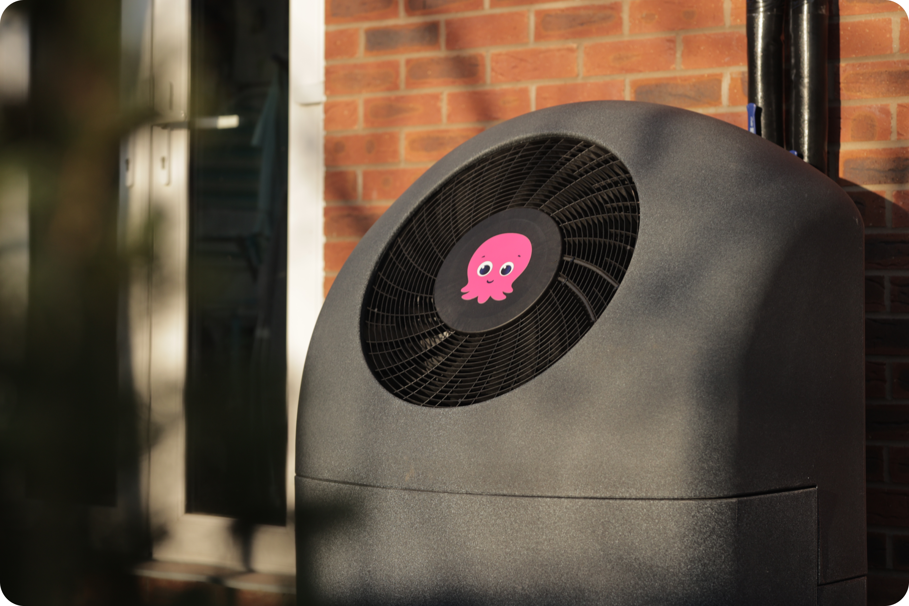 Grey cosy heat pump with pink constantine in the middle against brick wall