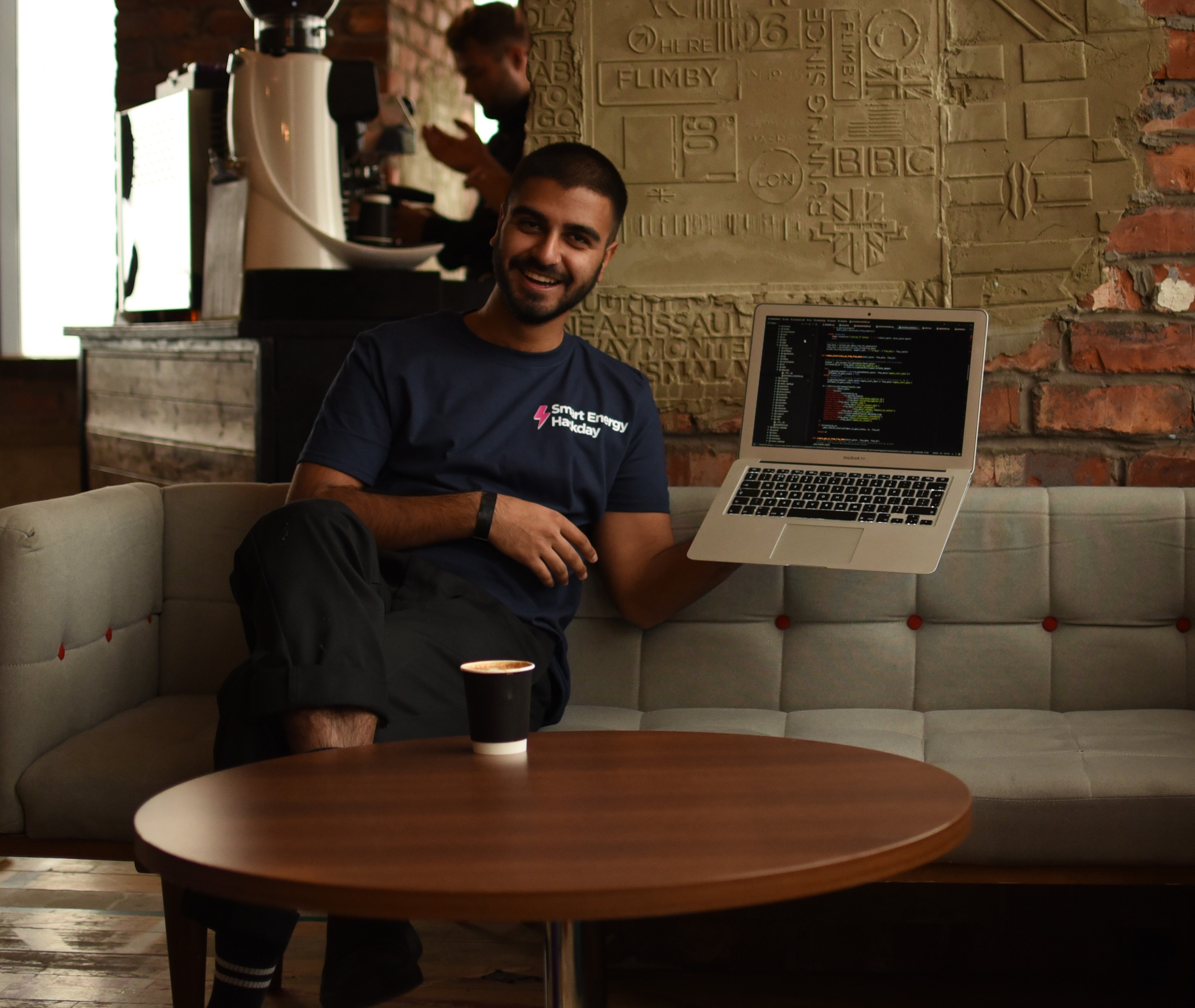 A photo of Suraj holding up a laptop at the office