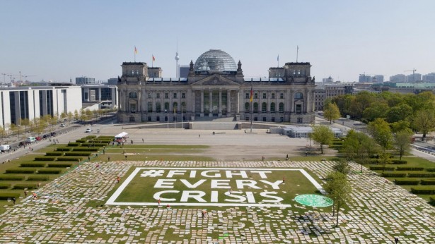 placards arranged outside a government building in Germany. They spell out 'Fight every Crisis'.