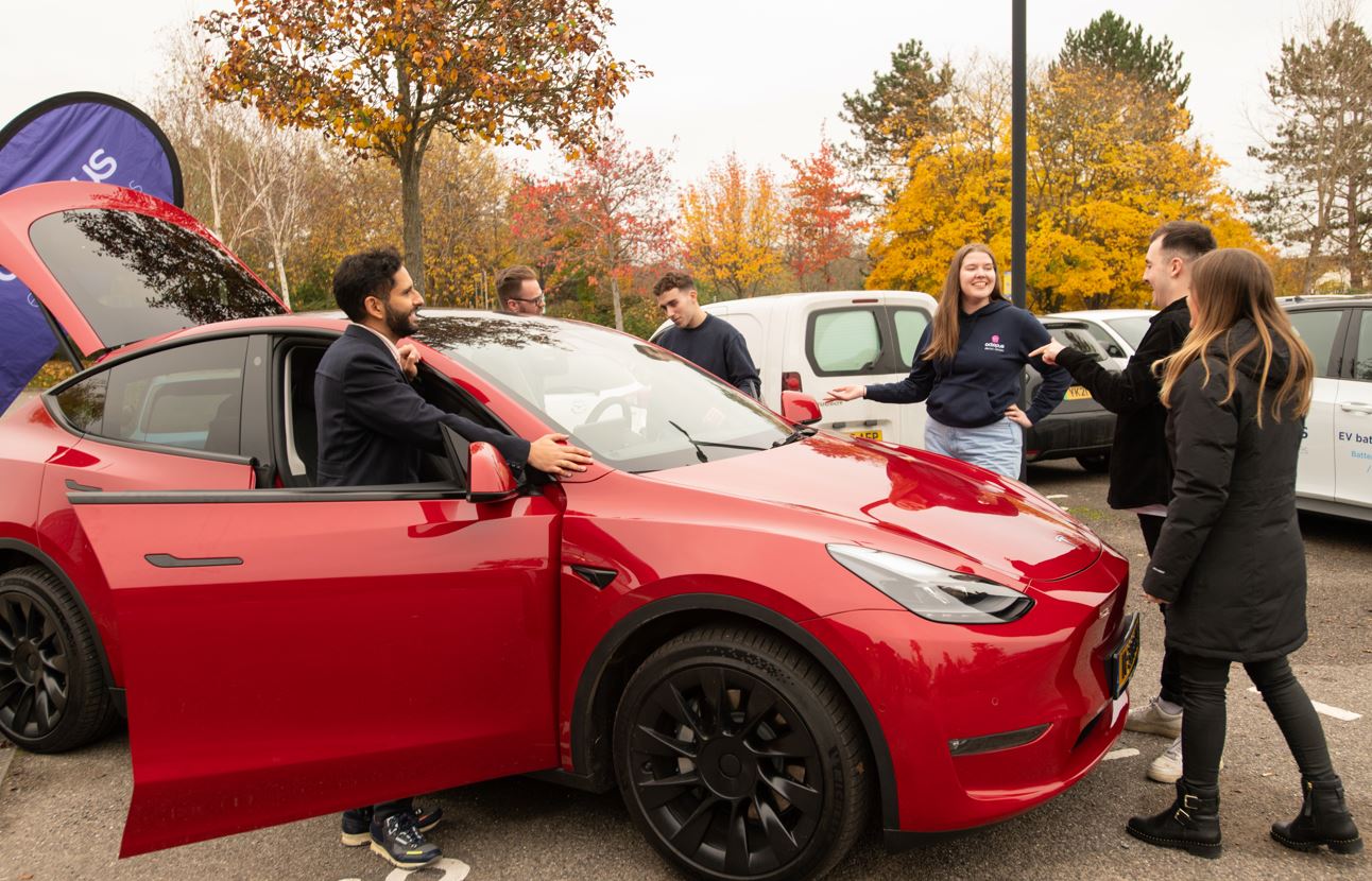Gurjeet and the OEV Team standing by a red electric car and chatting