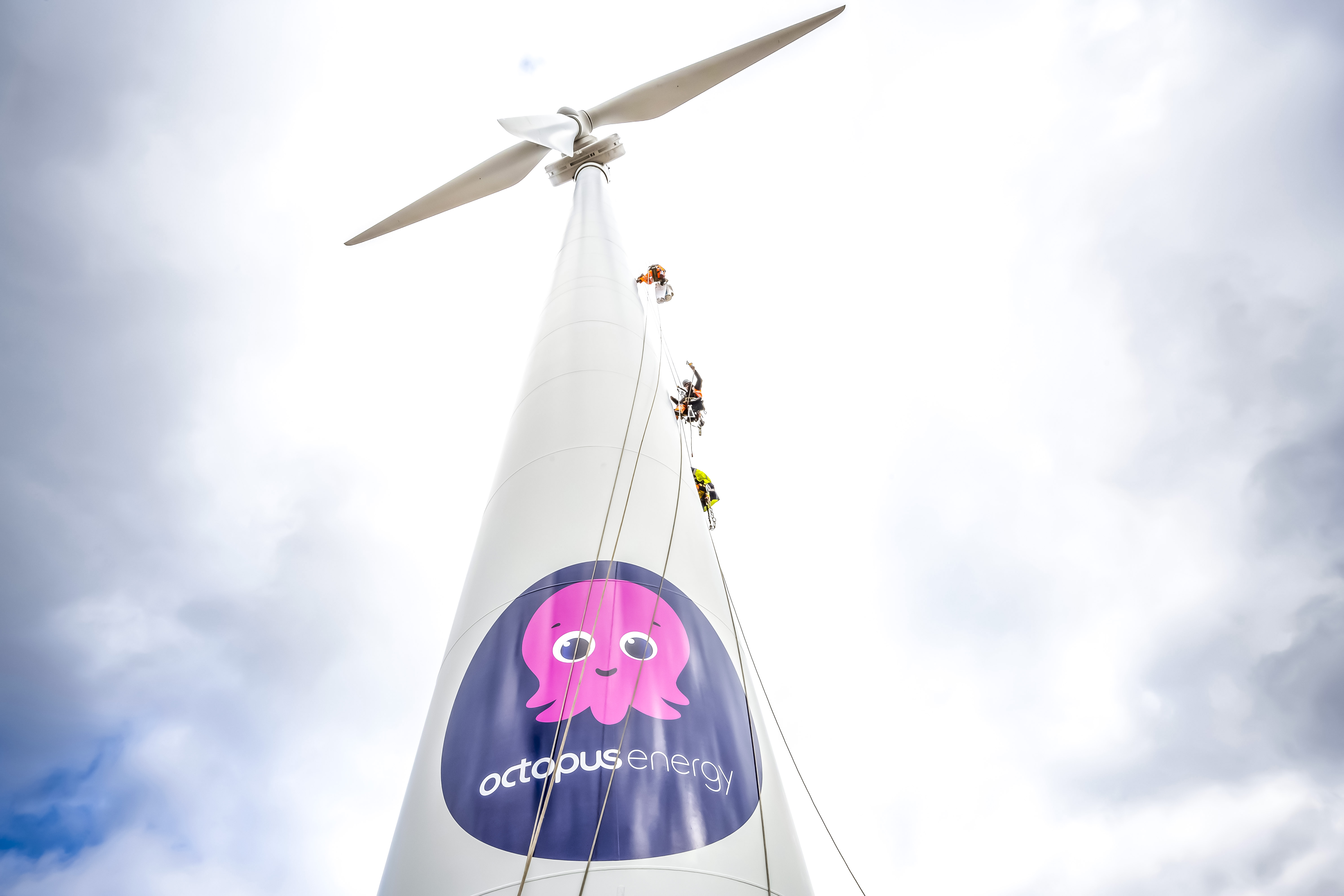 A photo of brave sign writers attaching giant vinyl logos to our Octopus wind turbine