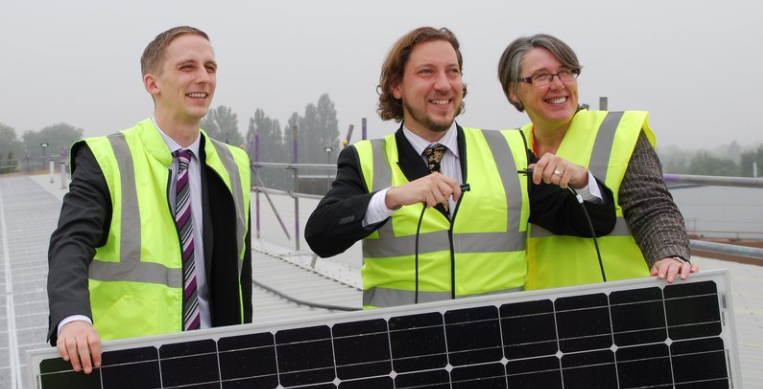 An image of three oxford community energy enthusiasts holding a solar panel on the roof their hq