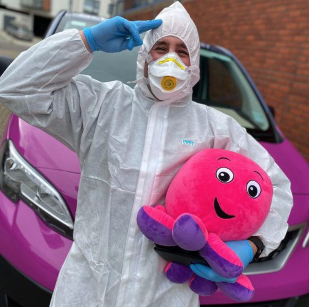 A picture of our engineer Jez in a hazmat suit with a toy octopus