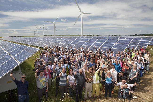 An image showing a group of community members standing amongst the solar panels and turbines at westmill