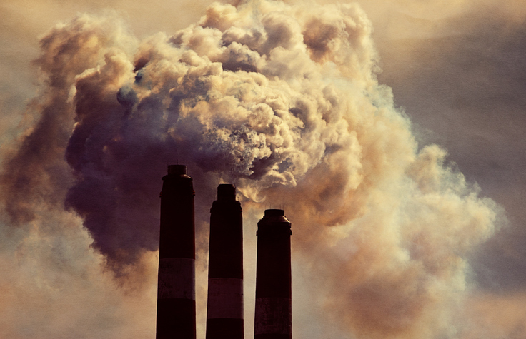Image of three industrial chimneys billowing smoke