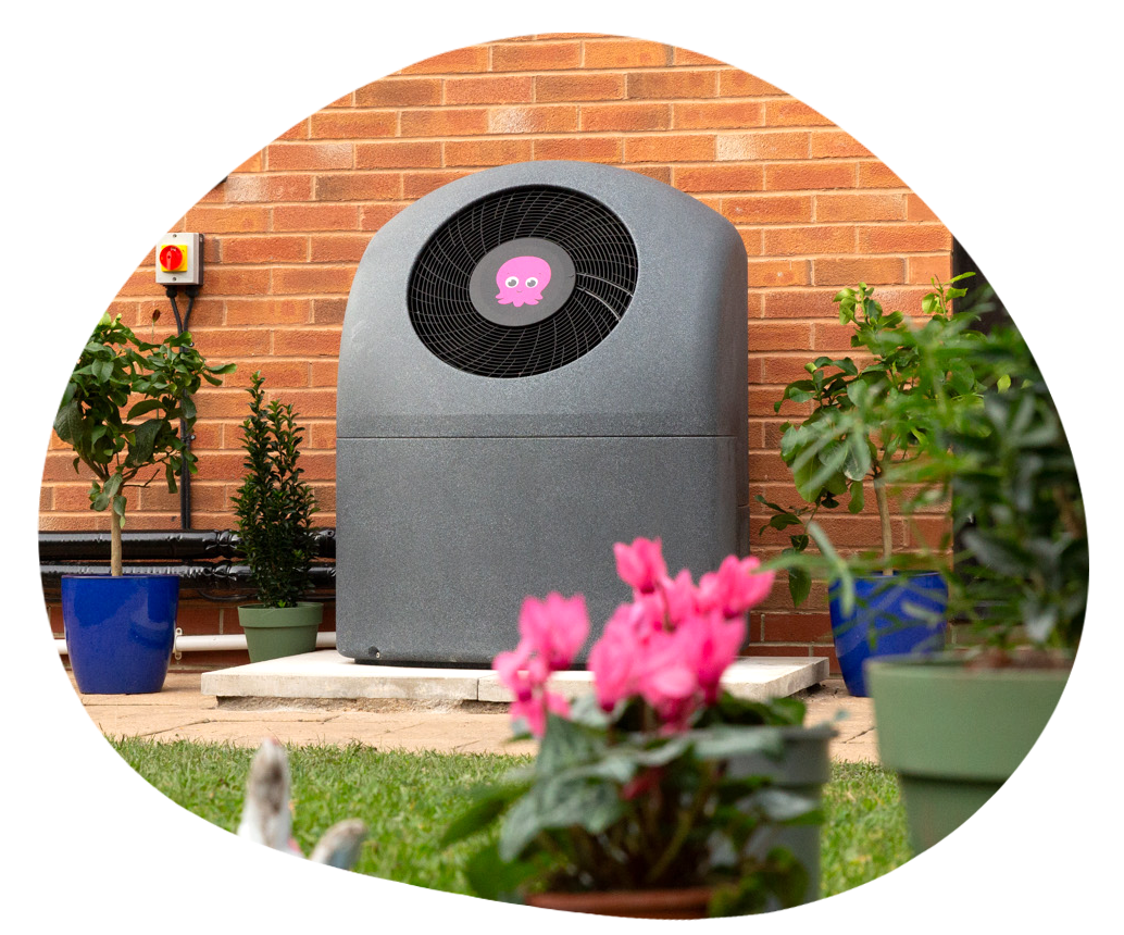 Heat pump in garden next to pink flowering plant
